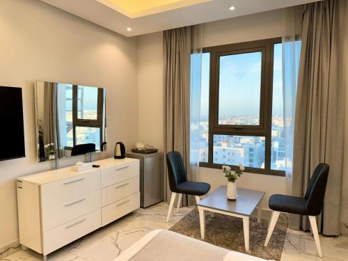 a living room with a dresser and two chairs at Al Safwa One in Al Ḩadd