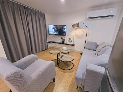 a living room with a couch and chairs and a tv at 10 Angels in Christchurch