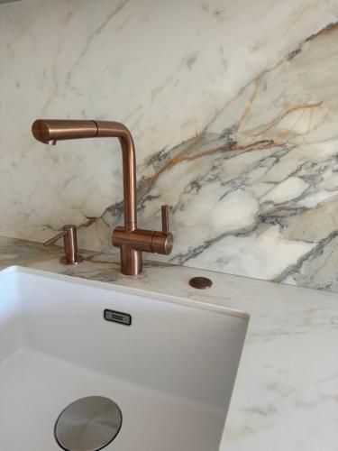 un robinet en cuivre sur un évier blanc dans l'établissement Appartement face au port, à Antibes