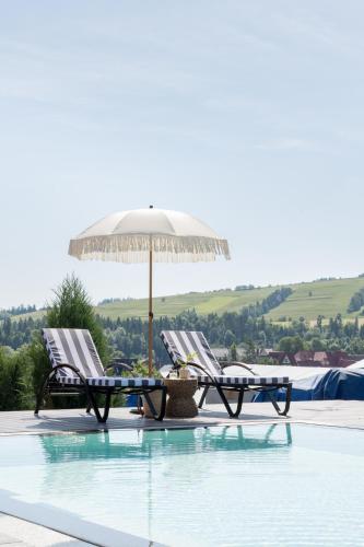 two chairs and an umbrella next to a swimming pool at Domki w Białce WOODHOUSE- Twój górski azyl przy stoku in Białka Tatrzańska