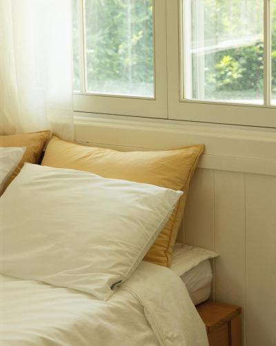 a bed with white sheets and pillows next to a window at Soomhouse in Danyang