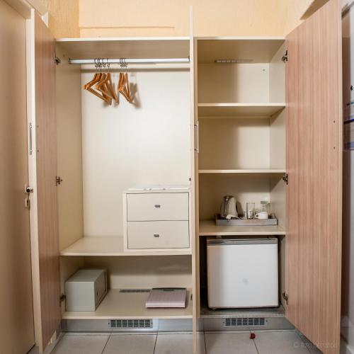 a small kitchen with white cabinets and shelves at Porto Skala Village Hotel in Skala Kefalonias