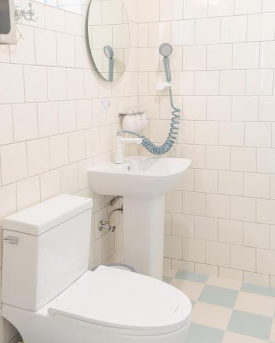 a white bathroom with a toilet and a sink at Soomhouse in Danyang