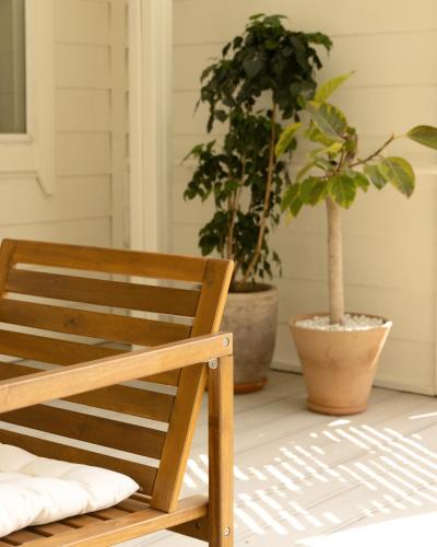 a wooden chair sitting on a porch with two potted plants at Soomhouse in Danyang