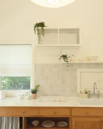 a white kitchen with a sink and a window at Soomhouse in Danyang