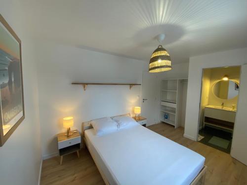 une chambre avec un grand lit blanc et une salle de bain dans l'établissement Maison bord de mer à Etel, à Étel