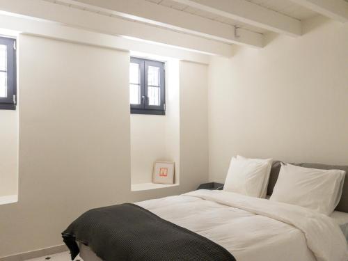 a bedroom with a bed with white walls and windows at Bigtrel Athens in Athens