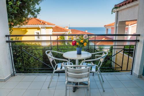 a table and chairs with a vase of flowers on a balcony at Porto Skala Village Hotel in Skala Kefalonias