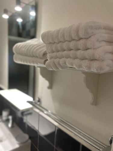 - une pile de serviettes sur une étagère dans une salle de bains dans l'établissement Appartement cosy en centre ville, à Semur-en-Auxois