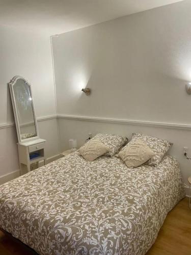 une chambre avec un lit avec deux oreillers et un miroir dans l'établissement Appartement cosy en centre ville, à Semur-en-Auxois