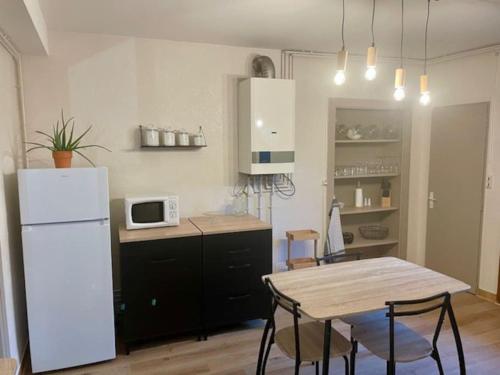 une cuisine avec une table et un réfrigérateur blanc dans l'établissement Appartement cosy en centre ville, à Semur-en-Auxois