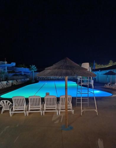 - un groupe de chaises et un parasol à côté de la piscine dans l'établissement Camping les Charmettes, aux Mathes