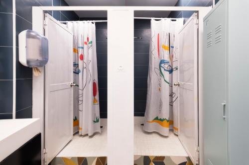a bathroom with two shower stalls with white curtains at Home Youth Hostel by Feetup Hostels in Valencia