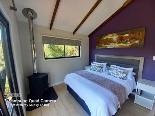 a bedroom with a bed and a purple wall at Birdsong Cottage No 10 10 Poplar Drive Bergview Estate Cathkin Park in Champagne Valley