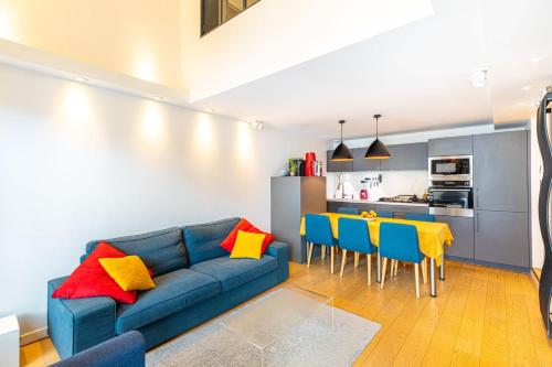 un salon avec un canapé bleu, une table et des chaises dans l'établissement GuestReady - Colourful Getaway near Eiffel Tower, à Paris