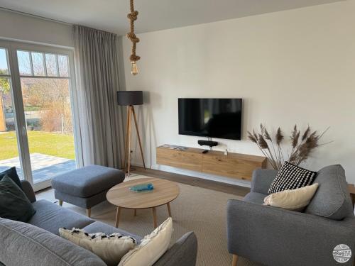 a living room with two couches and a flat screen tv at Ferienhaus Hornhecht in Born