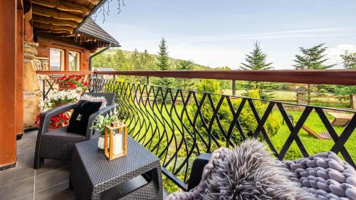 a balcony with chairs and a table and a fence at Aparthotel Delta Boutique in Kościelisko