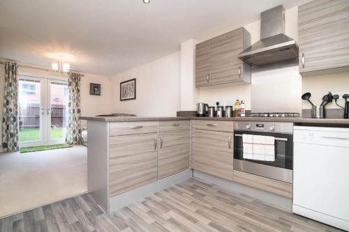 a large kitchen with wooden cabinets and appliances at Quiet Two Bedroom House Driveway Parking & Garden in Wolverhampton
