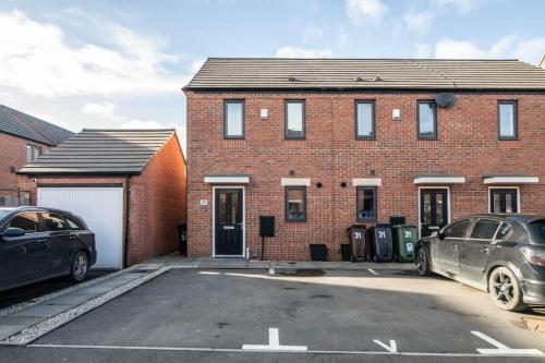 a brick house with two cars parked in a parking lot at Quiet Two Bedroom House Driveway Parking & Garden in Wolverhampton