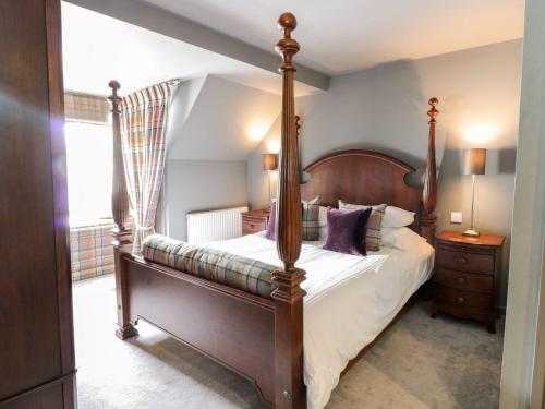 una camera da letto con un letto a baldacchino con cuscini viola di Wee Cottage a Moffat
