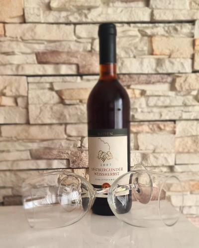 a bottle of wine with glasses next to a brick wall at RingPeace Apartment, Dubrava - free parking in Zagreb