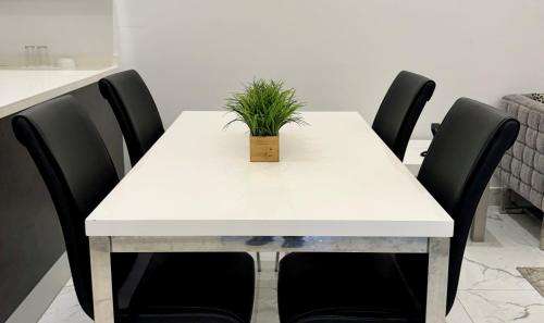 a white table with black chairs and a plant on it at Al Safwa One in Al Ḩadd