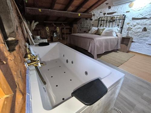 a bath tub in a room with a bed at Casa rural La calleja de las hurdes TRCC00555 in Sauceda