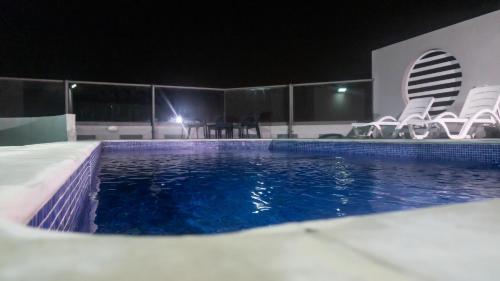a swimming pool at night with chairs around it at Al Safwa One in Al Ḩadd