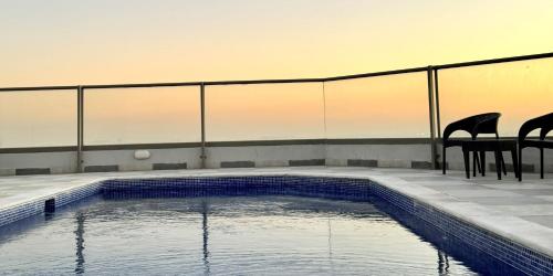 a swimming pool with two chairs and a fence at Al Safwa One in Al Ḩadd