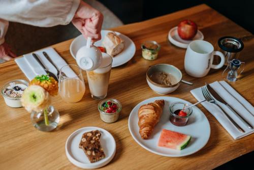 a table with plates of breakfast foods and a person pouring coffee at Witte Berken Natuurhotel in Epe