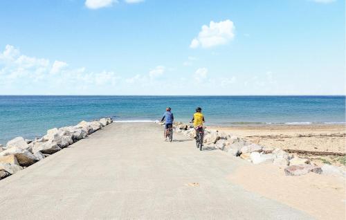 two people riding bikes down a path on the beach at 3 Bedroom Beautiful Home In Lessay in Lessay