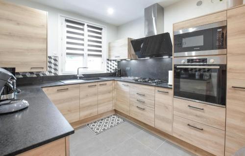 a kitchen with wooden cabinets and a stove top oven at 3 Bedroom Beautiful Home In Lessay in Lessay