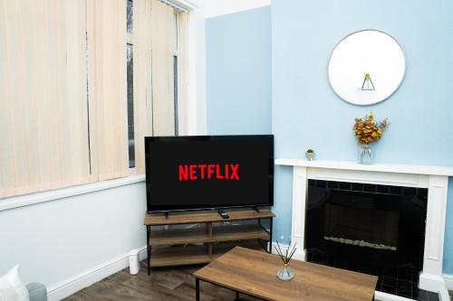 a living room with a tv and a fireplace at Leeds Large Townhouse Retreat Close to The City in Hunslet