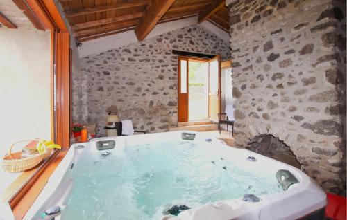 a large bath tub in a room with a stone wall at Pet Friendly Home In Privas With Sauna in Privas