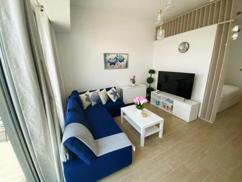 a living room with a blue couch and a tv at Yas Island Mayan 2 Junior 1 Bed Apartment with Private Beach Access by Central Stay in Abu Dhabi