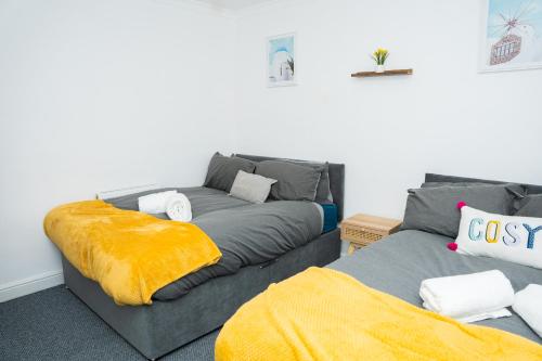 a living room with a grey couch with a yellow blanket at Leeds Large Townhouse Retreat Close to The City in Hunslet