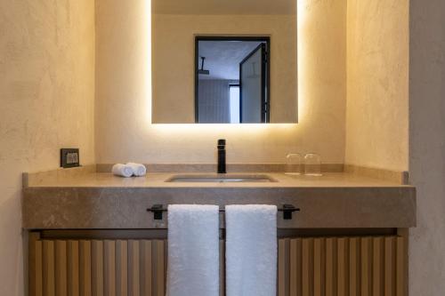 a bathroom with a sink and a mirror and towels at Radisson Blu Hotel, Kas in Kas