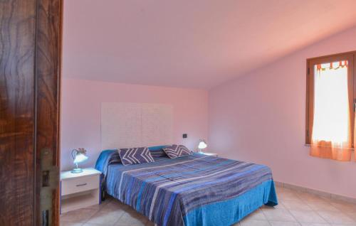 a bedroom with a bed with a blue comforter and a window at Lovely Apartment In Ilbono With Wifi in Ilbono