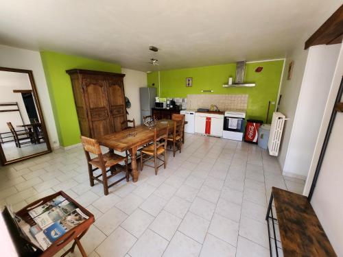 une cuisine avec des murs verts et une table et des chaises dans l'établissement Maison au calme, idéalement située au centre du Cotentin, à Le Dézert