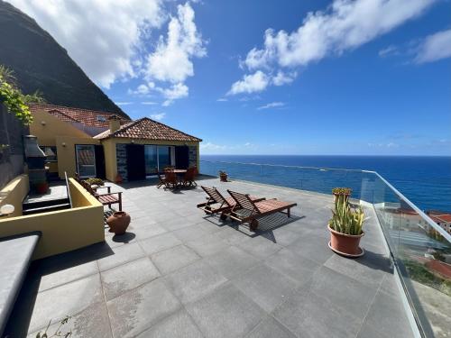 a patio with benches and a view of the ocean at Refúgio do Ilhéu in Porto Moniz