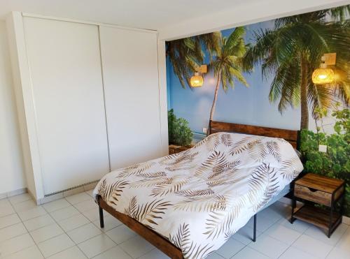 - une chambre avec un lit et un palmier dans l'établissement Appartement 2 chambre et terrasse, à Caux
