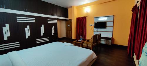 a bedroom with a bed and a desk and a television at CHETAN INN HOTEL in Bhubaneshwar