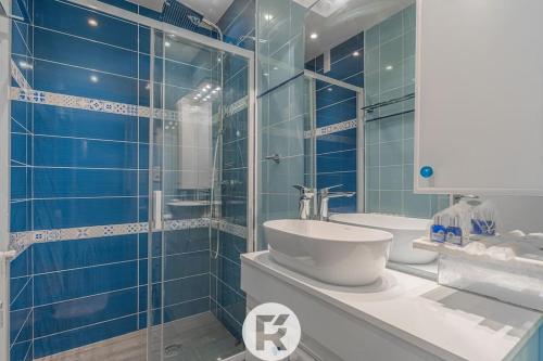 une salle de bain carrelée bleue avec un lavabo et une douche dans l'établissement R'Apparts T1 Petit Safari, à Grenoble