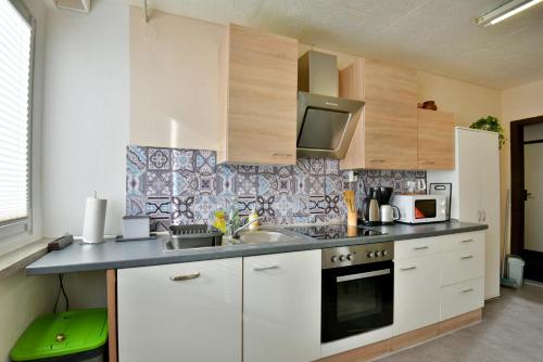 Una cocina con gabinetes blancos y un horno de estufa. en Monteurwohnung Steinsfeld Suhl, en Suhl
