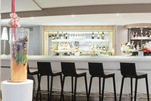 a bar with black chairs in front of a counter at Novotel Genève Centre in Geneva