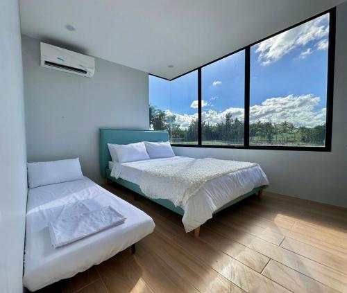 a bedroom with two beds and a large window at Experience Elements CherryBlossoms, Pool,SunRoom in Silang