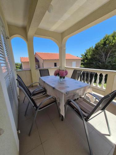 a table and chairs on a balcony with a vase of flowers at Apartments Velinka in Rab