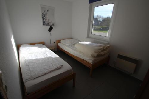 two beds in a small room with a window at Möwe 14 in Mirow