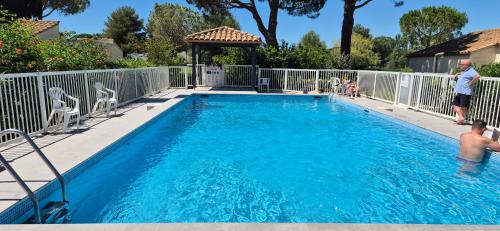 un homme debout à côté d'une piscine dans l'établissement Villa 40m2 cosy avec piscine, clim, parking privé, à La Grande Motte