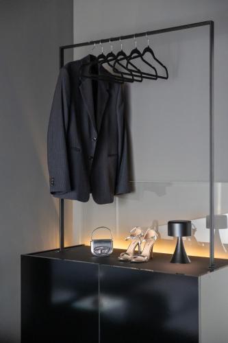 a dressing room with a mirror and a black suit and shoes at ETERN Apart-Hotel II in Pristina